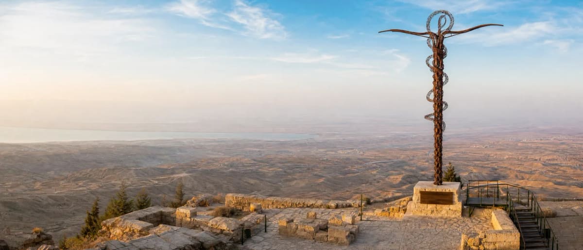 The Serpentine Cross monument on Mount Nebo overlooking the Jordan Valley toward the Dead Sea at sunset